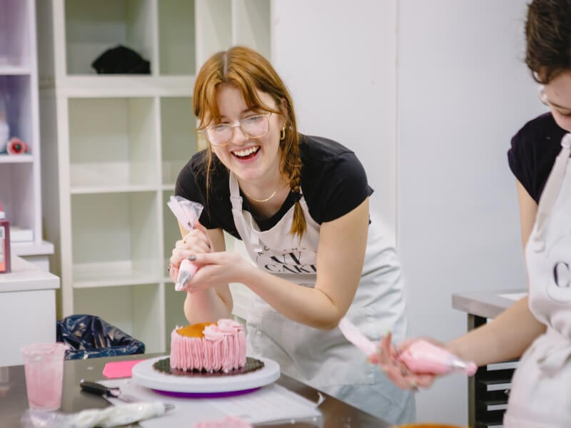 Student smiling and laughing at a cake decorating class