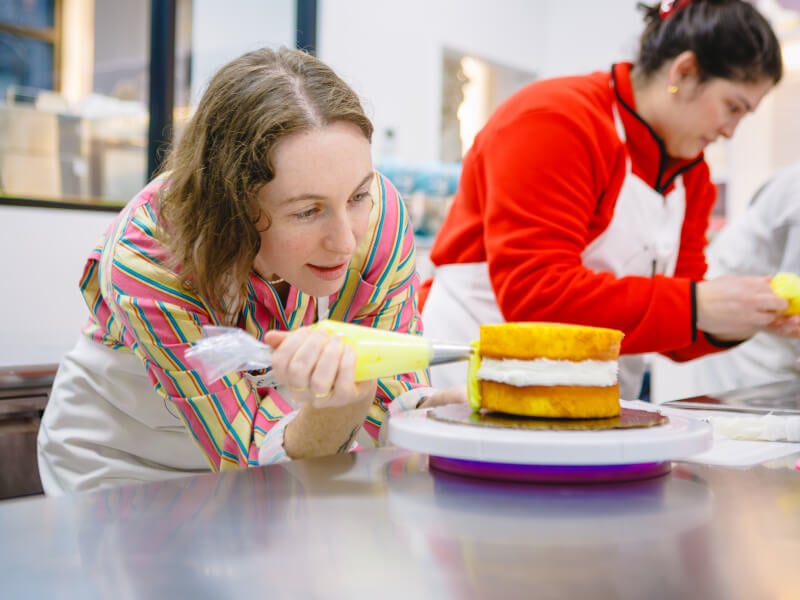 A student icing a cake at a cake decorating class