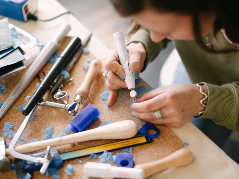 A close up of a person using a tool to make jewellery