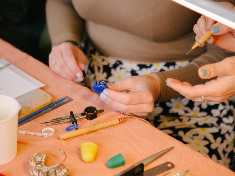 A close up of two hands holding a blue wax mould for ring making