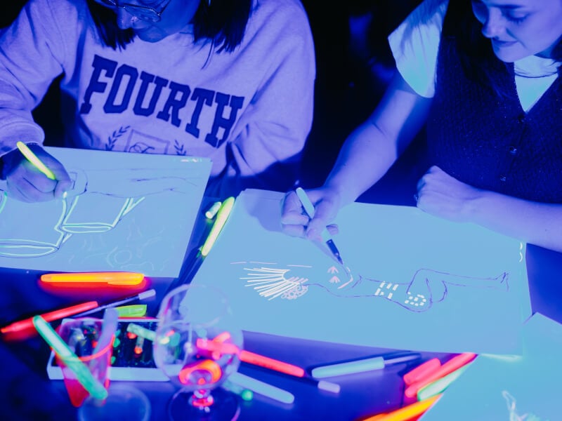Two women drawing at a neon life drawing workshop