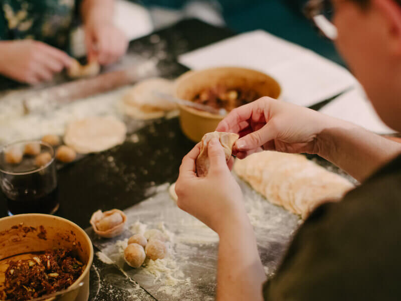 A close up of a person making a dumpling at a street food class
