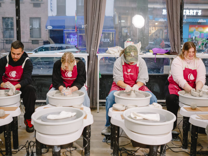 A group of students sitting at pottery wheels