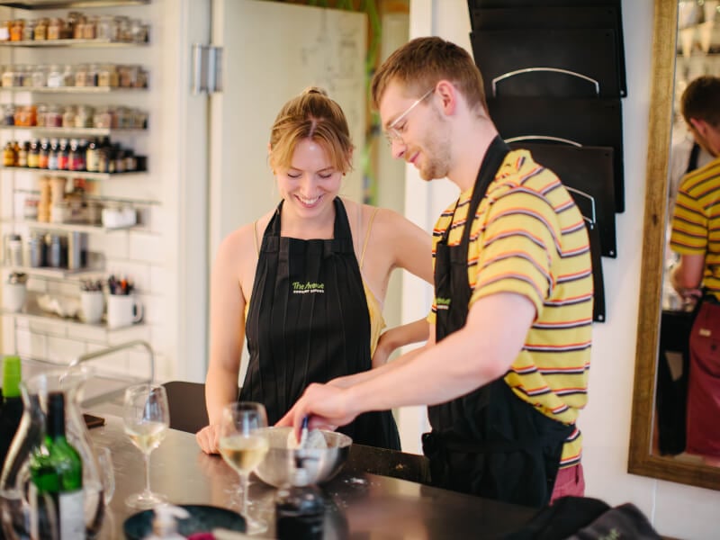 A man and woman at a cooking class are mixing ingredients in a bowl