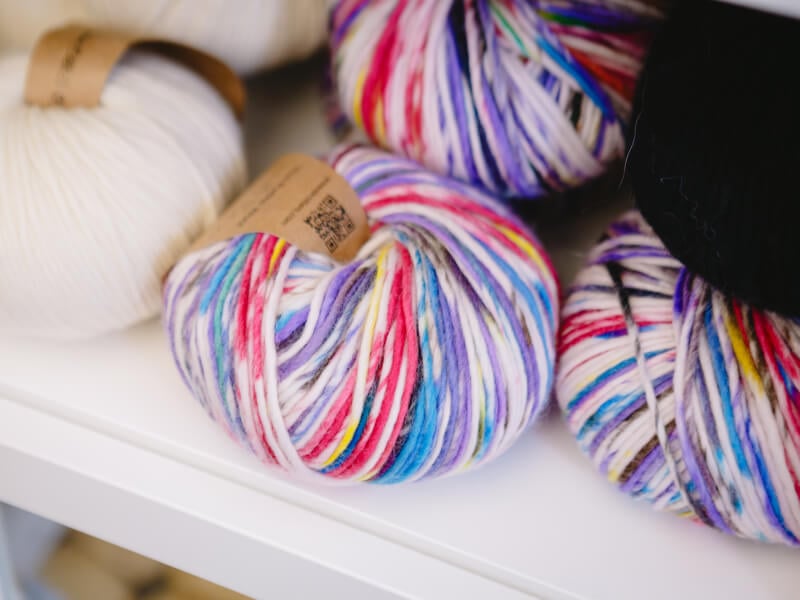 Colourful variegated yarn sits on a white shelf