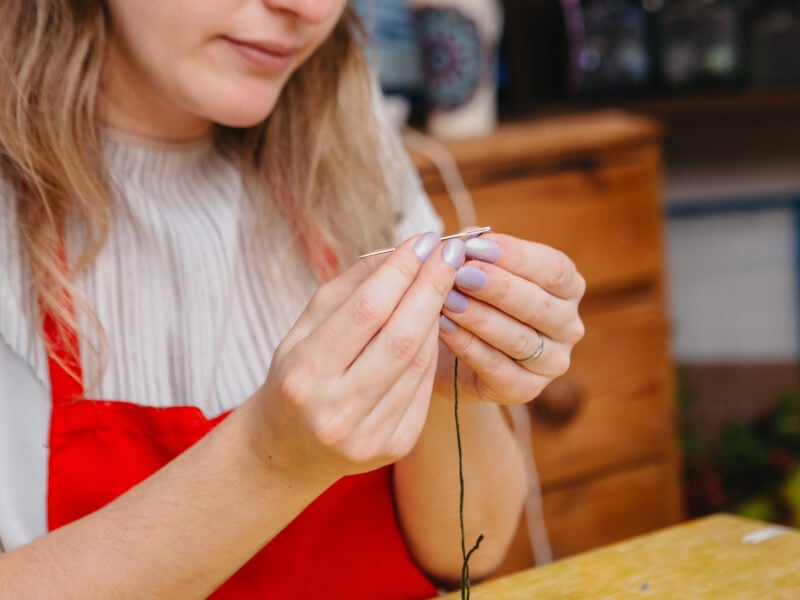 Close up image of woman holding thread and needle
