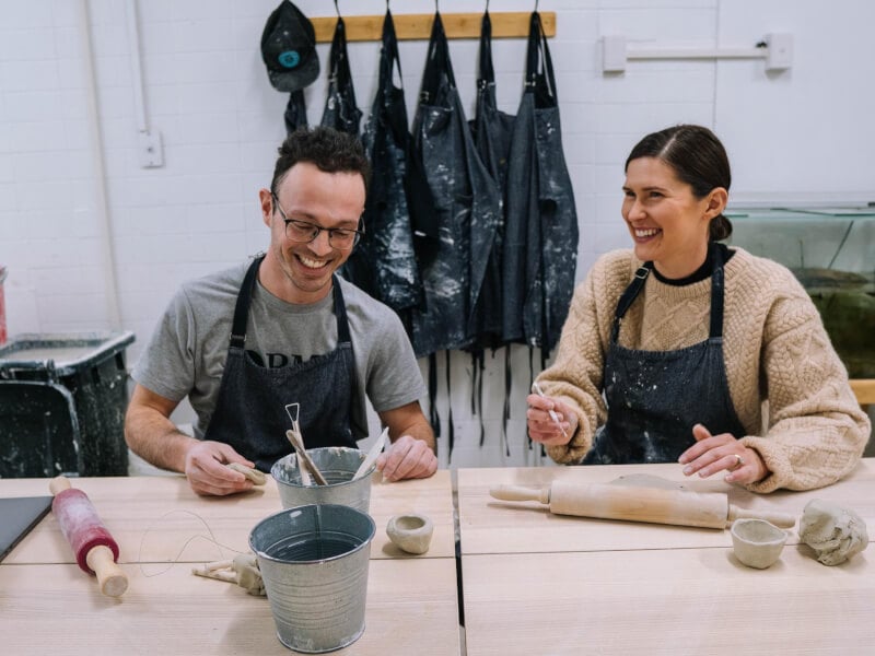 Two people laughing at a hand building pottery class