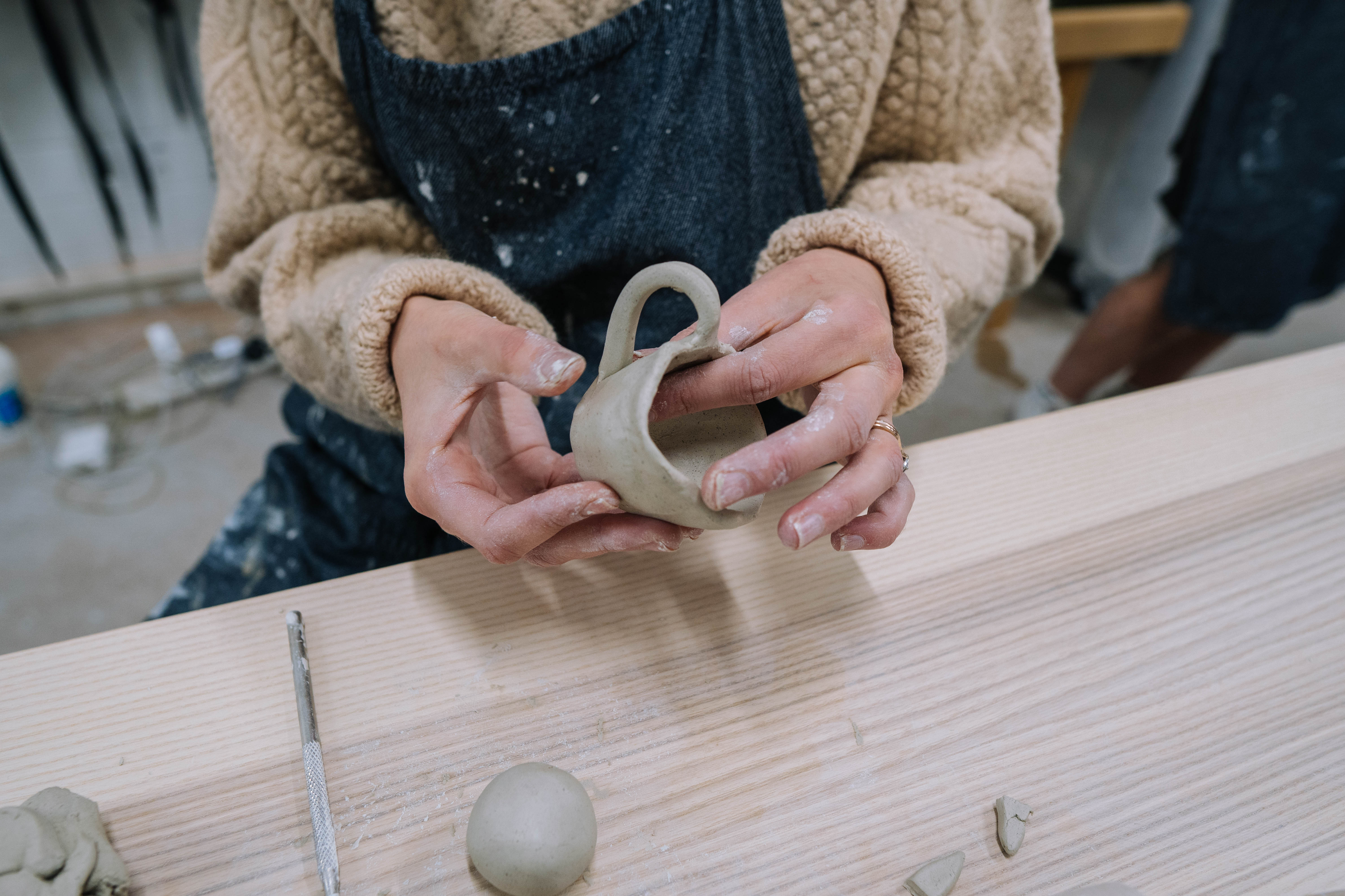 Close-up shot of hands moulding clay into a small cup.