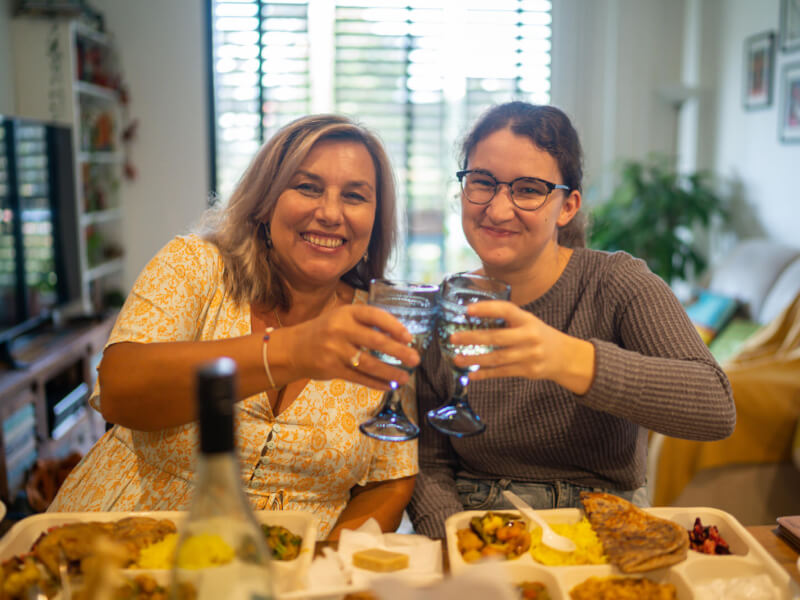 Two women are clinking glasses and smiling at a cooking class