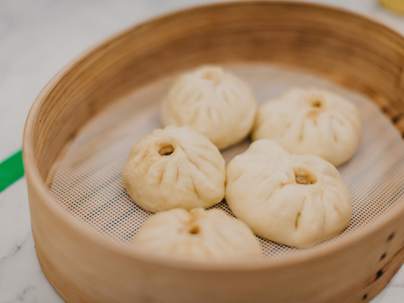 Homemade dumplings sit in a basket ready to be steamed