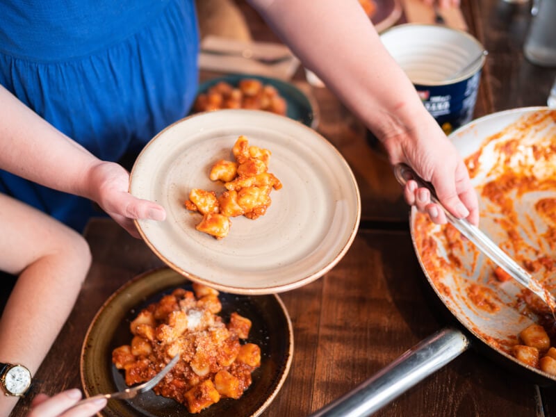 A person plates up some pasta made in an italian cooking class.