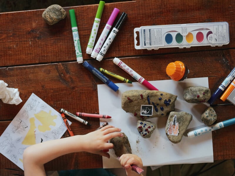A kid uses paints and pens to deocrate rocks