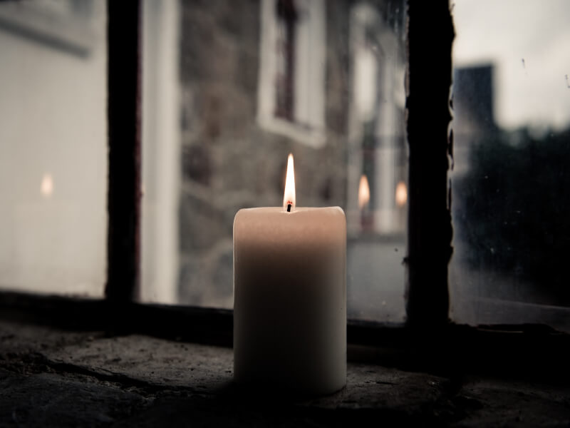 A lit candle in front of a glass window