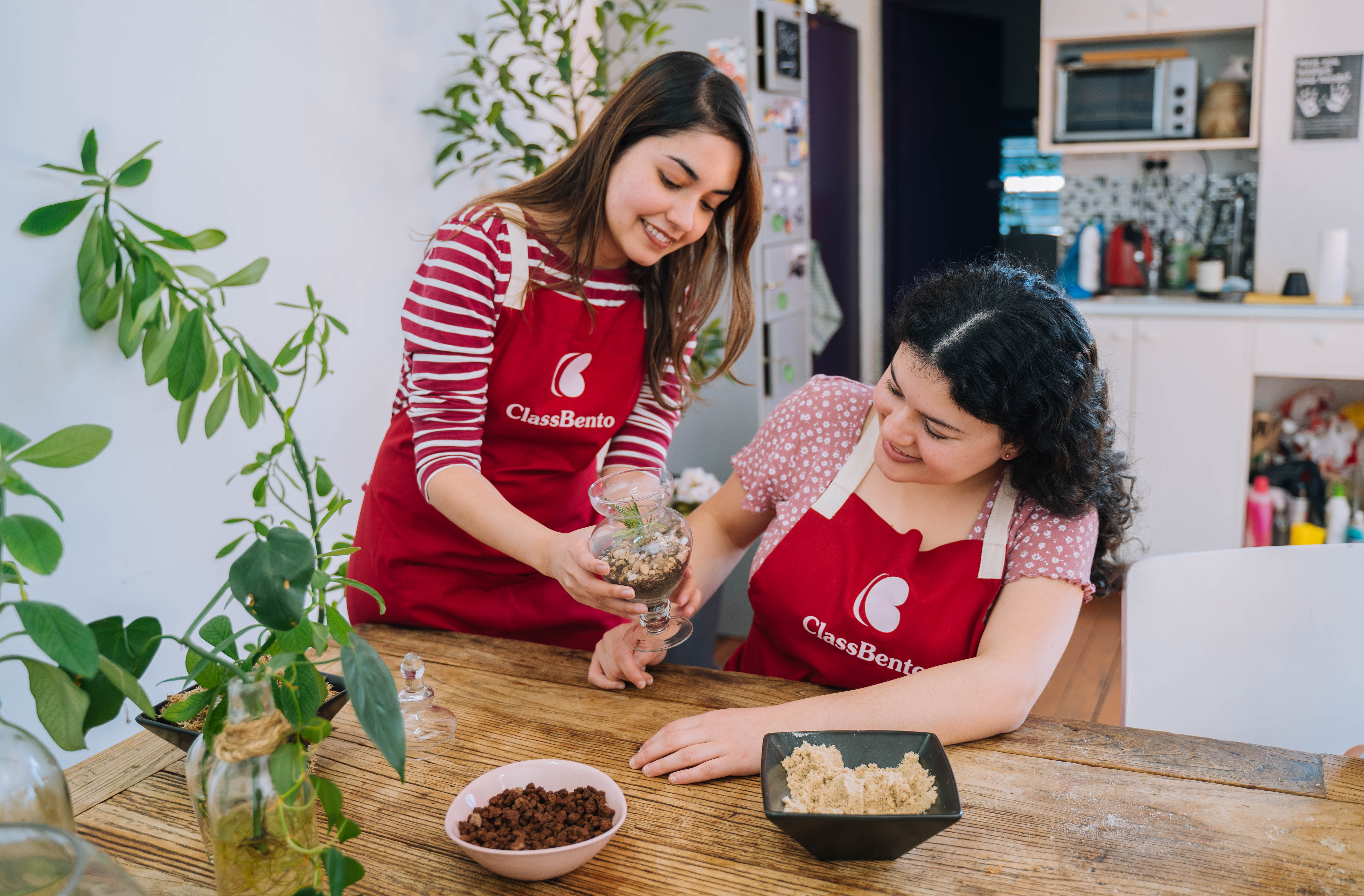 A teacher helps a woman making a plant terrarium