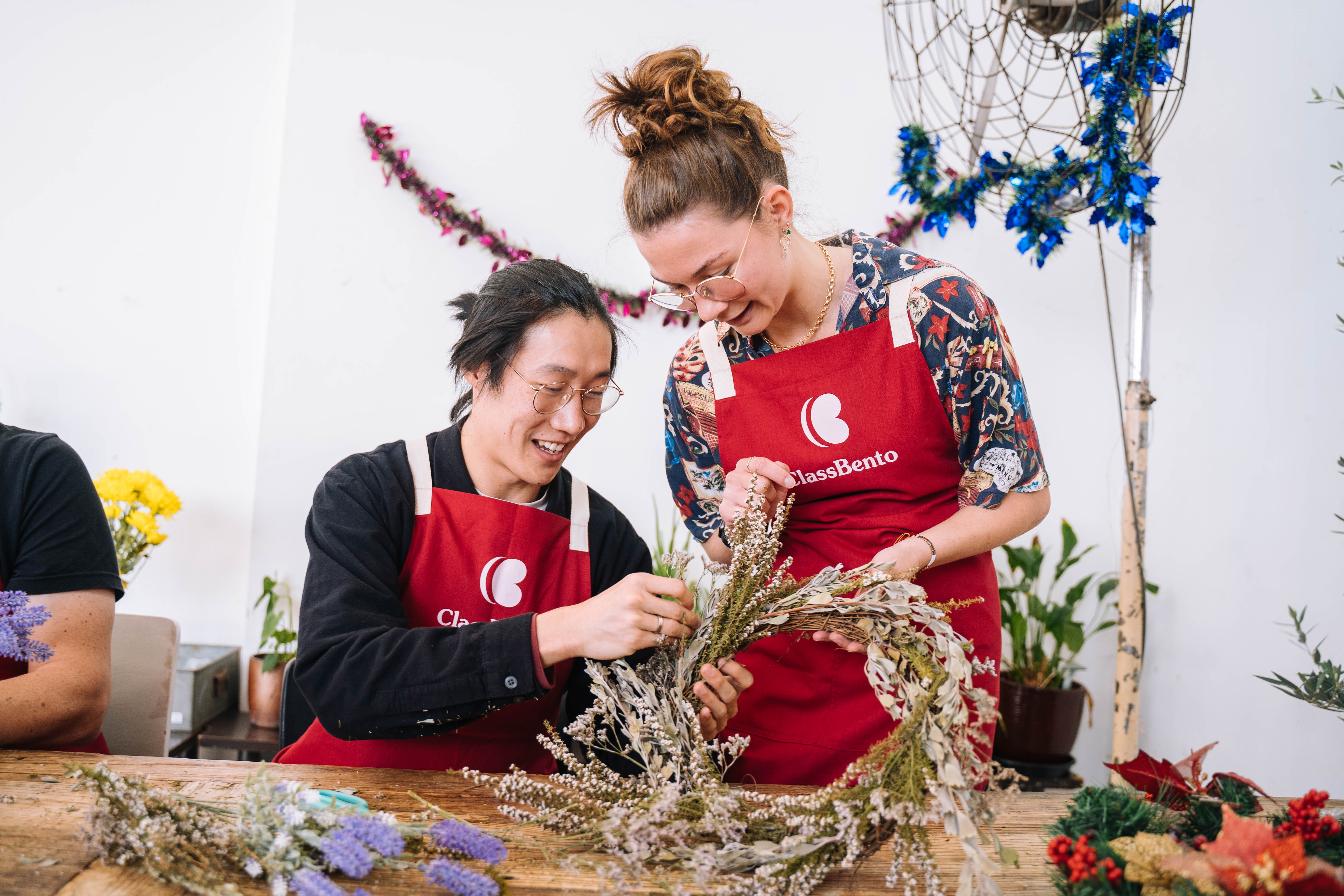 A man and a woman making a festive wreath of dried flowers