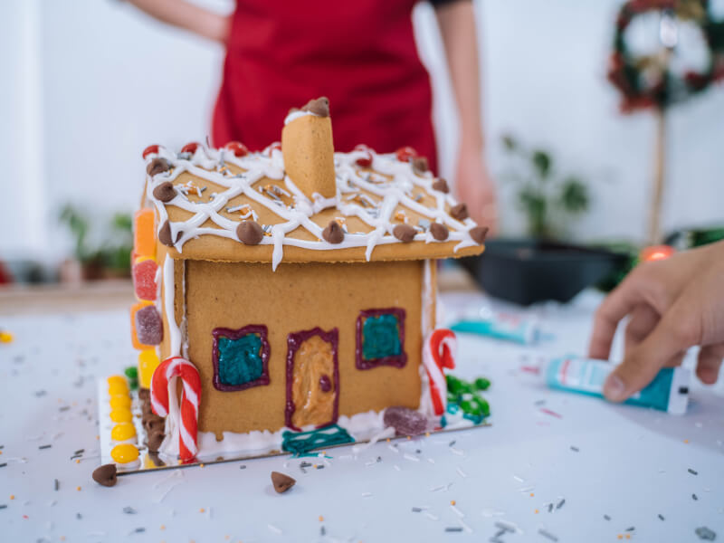 Gingerbread house decorated with icing, candy canes, jelly drops and chocolate nibs 