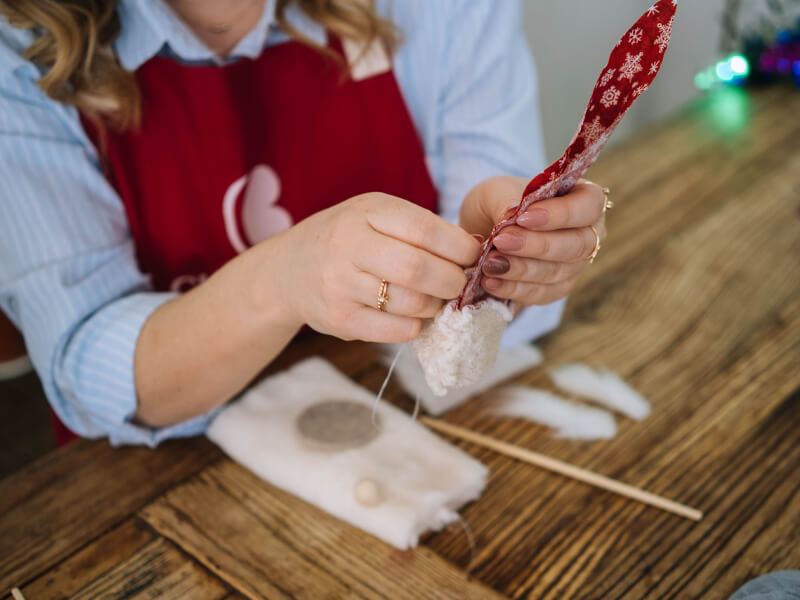 Person sewing a piece of patterned cloth with a faux-fur trim