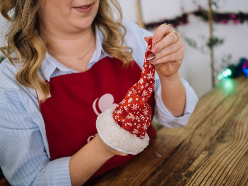 Close up of hands holding a small red Santa hat to be used as a Christmas decoration