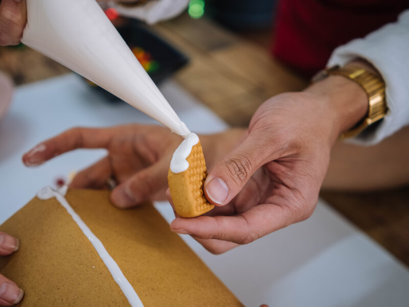 Close up of a person piping white icing onto a cookie