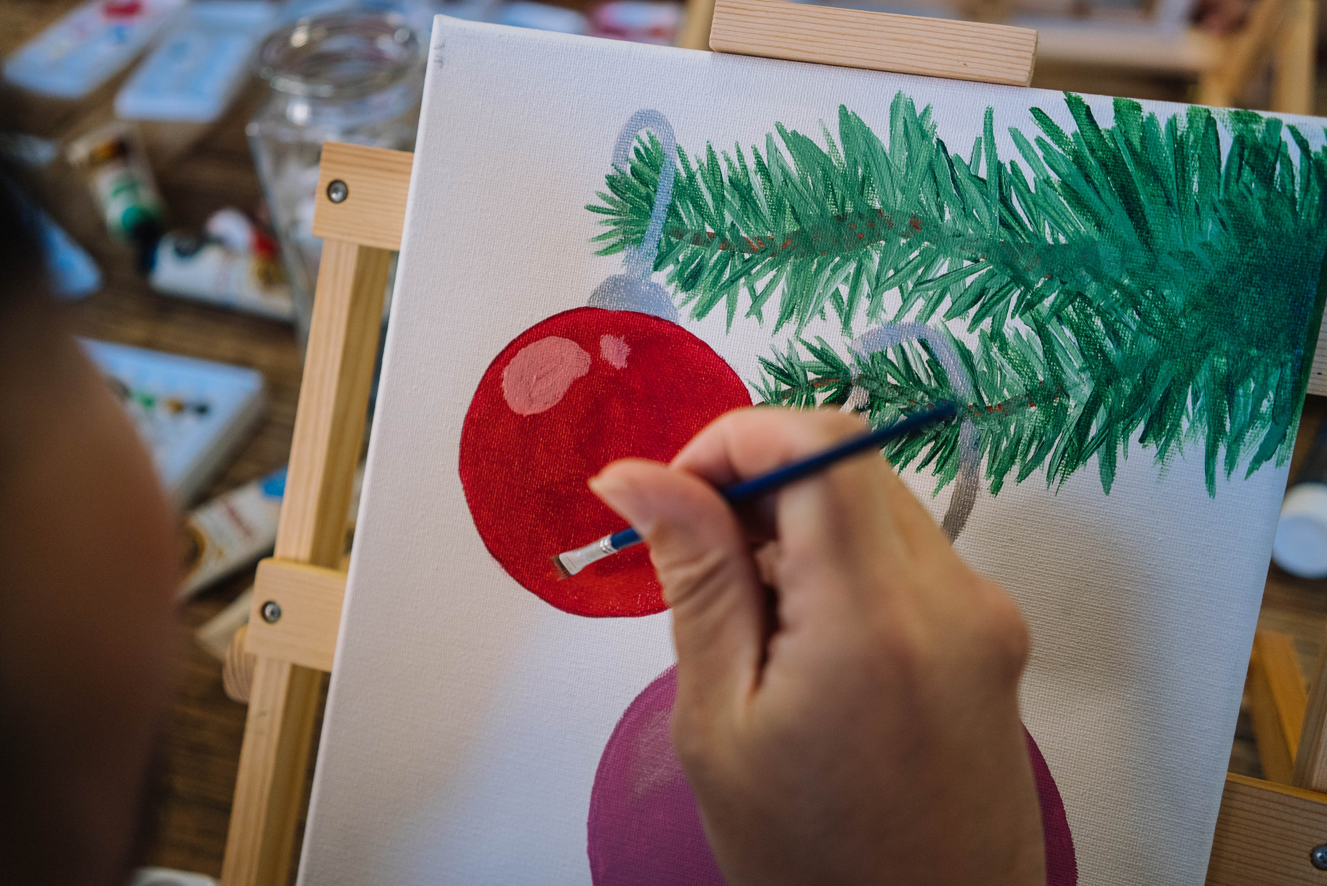 Close up of a hand painting some traditional Christmas motifs on canvas