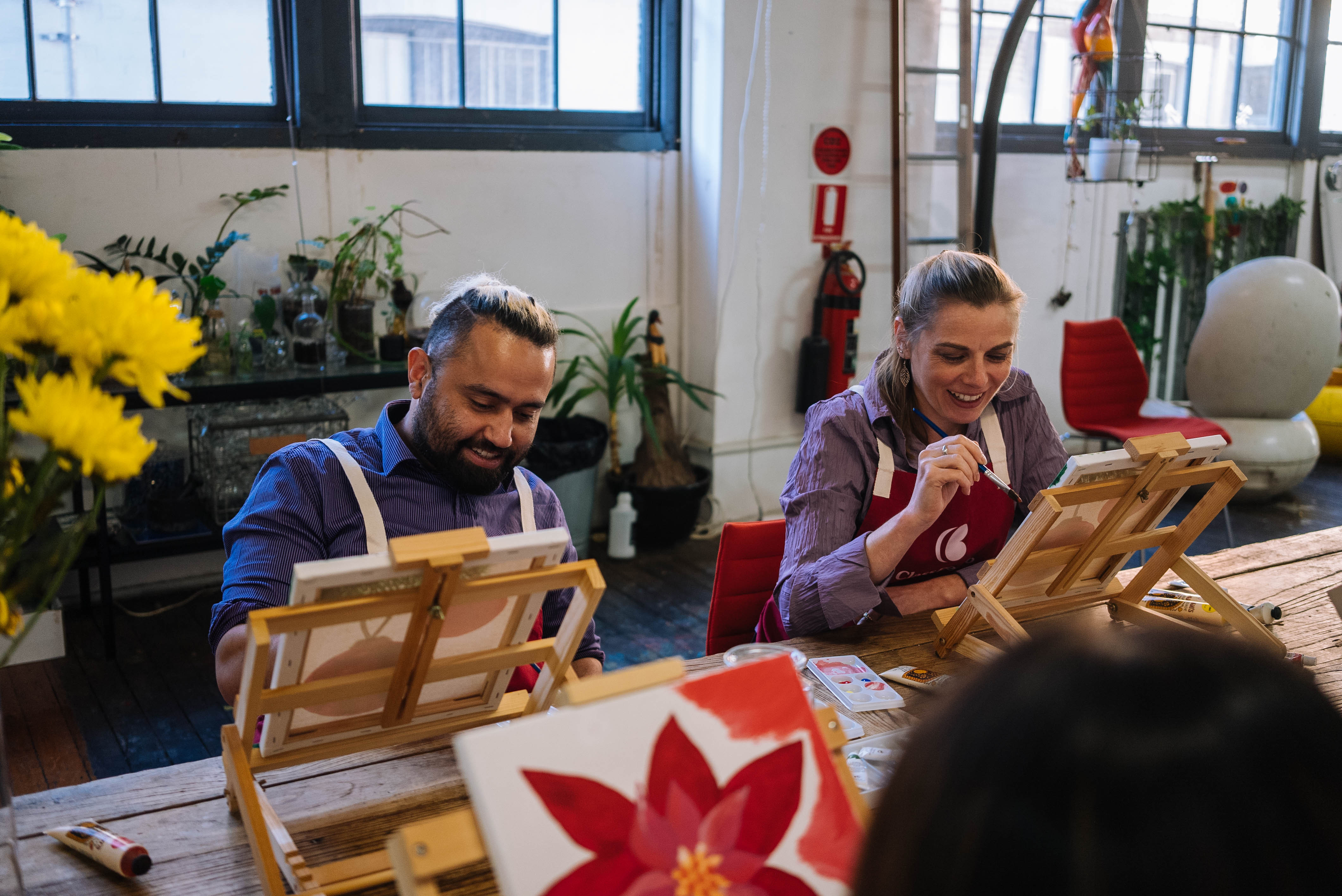 Two people painting together at a Christmas paint and sip class
