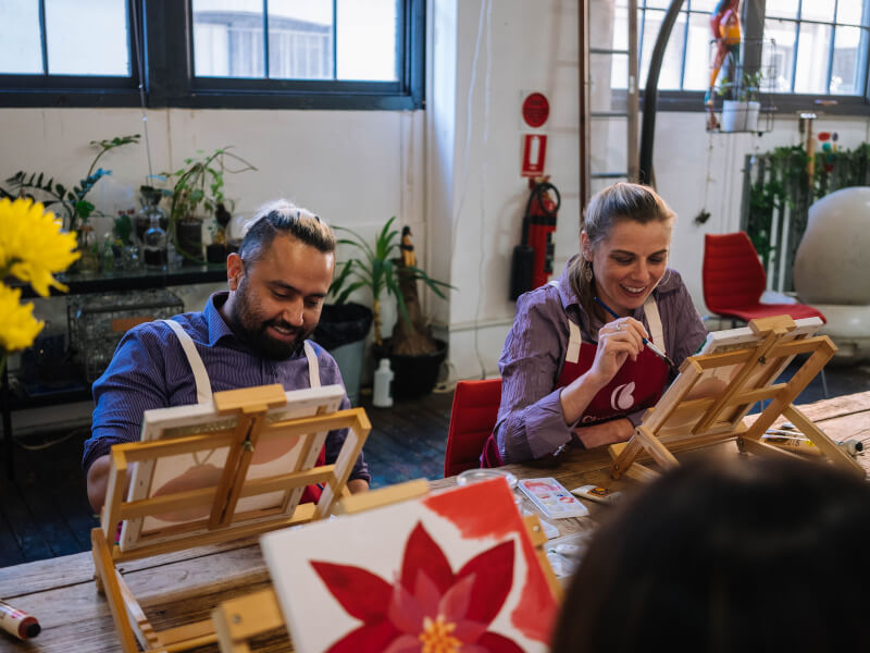 A man and woman smiling at a paint and sip class. 