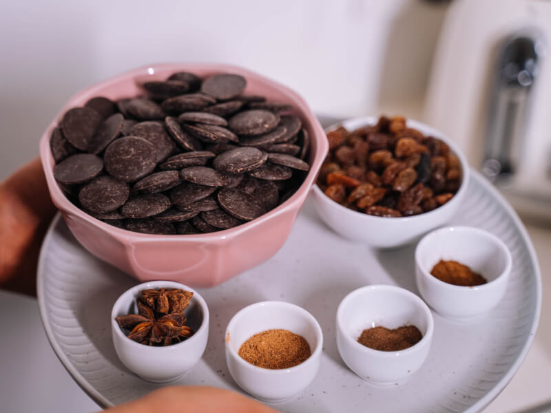 A selection of pale pink and white bowls containing chocolate buttons, star anise and powered spices ready for a baking and desserts workshop