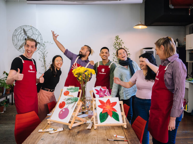 A group of people wearing aprons at a Christmas art class.