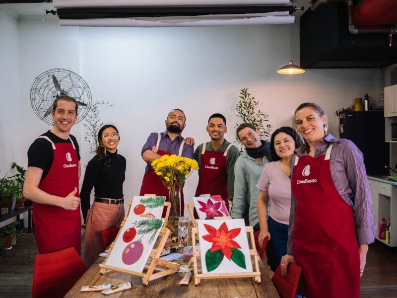 A team wearing red aprons at a team building painting class.