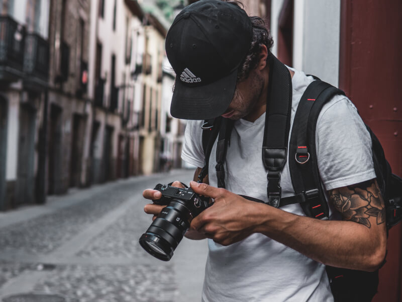 A man holding a DSLR camera on the street.