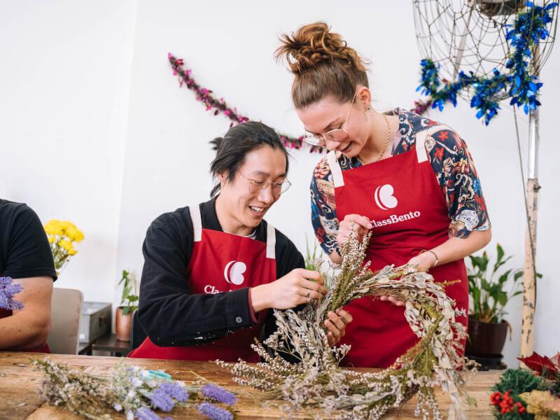 Couple making dried flower wreath at a craft class.