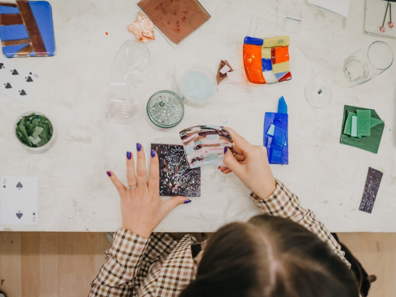 A top down view of someone making fused glass art in a workshop.