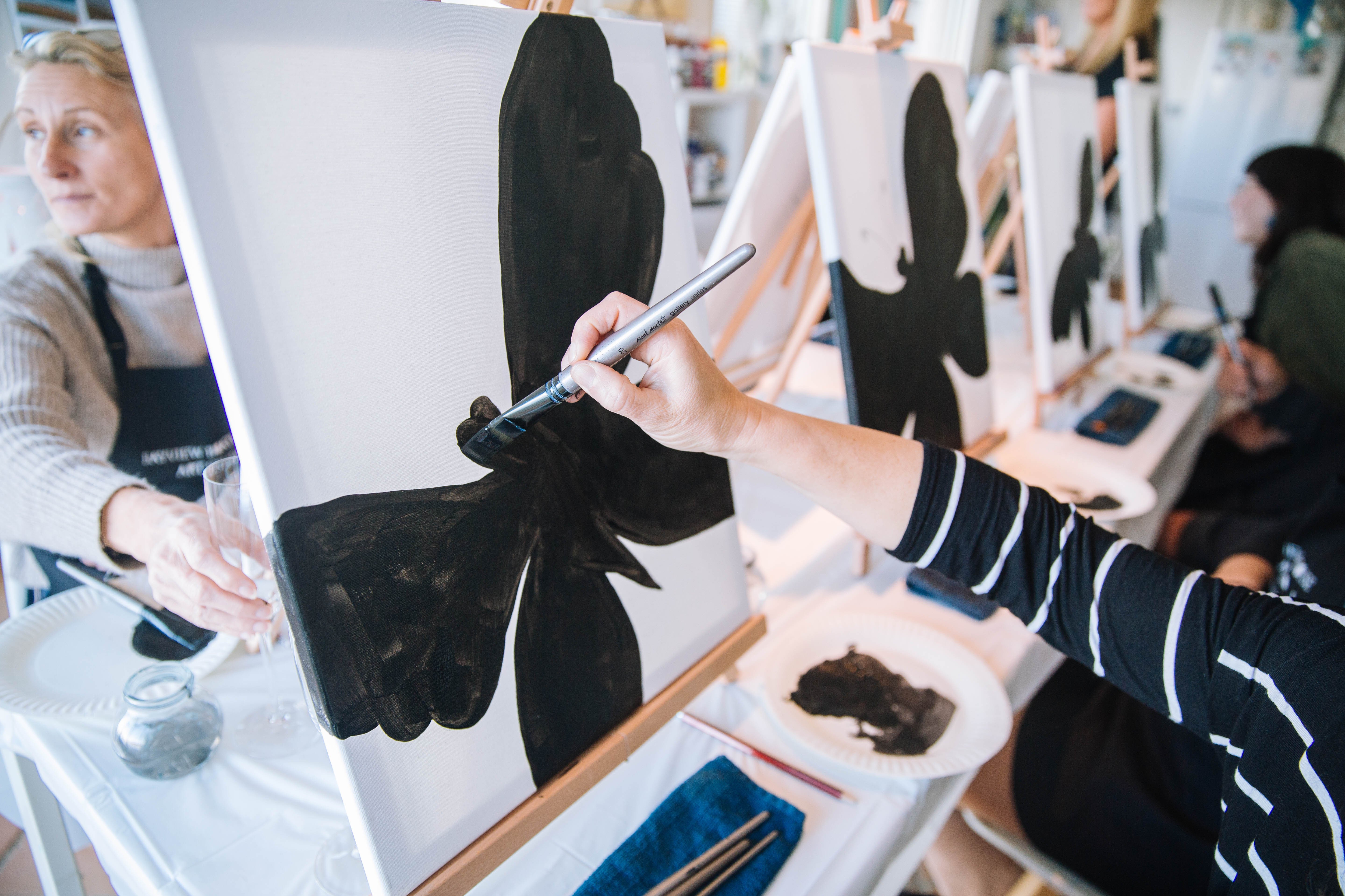 A black butterfly painted on a canvas at a paint and sip event.
