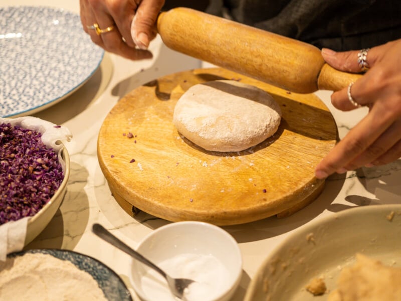 Hands rolling dough with a rolling pin in an Indian cooking class