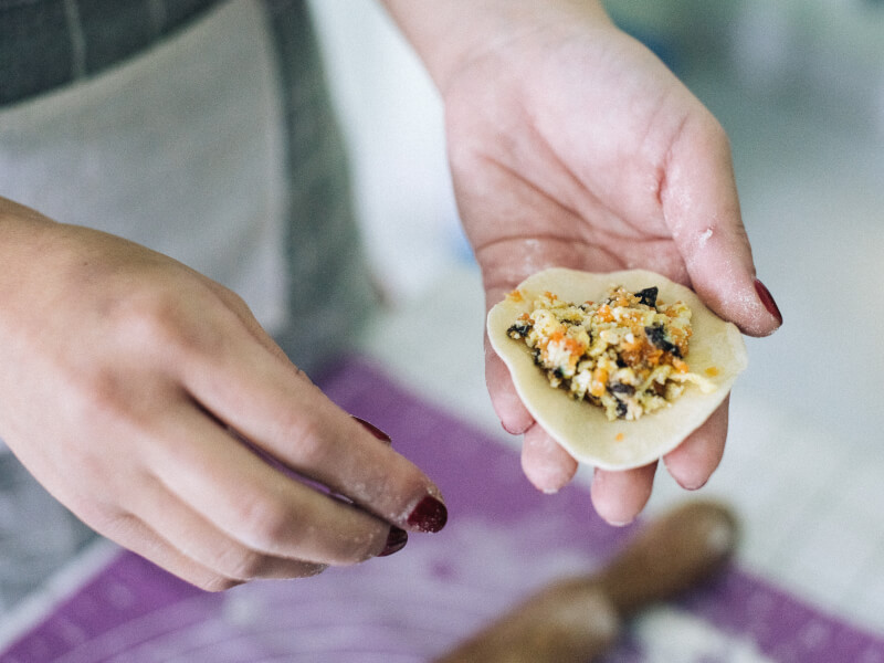 A close up of a person holding a handmade dumpling