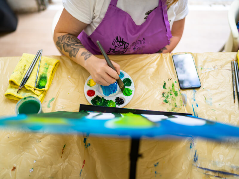 A person is painting a picture in shades of blue and green