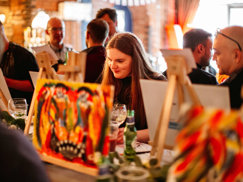 A group of people at an art class in Edinburgh are painting brightly coloured pictures at easels