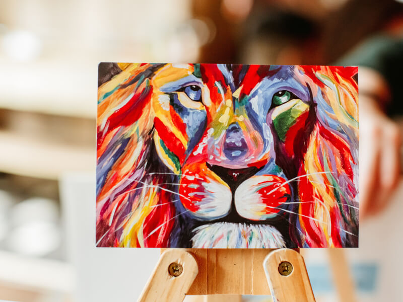 A brightly coloured painted picture of a lion on canvas
