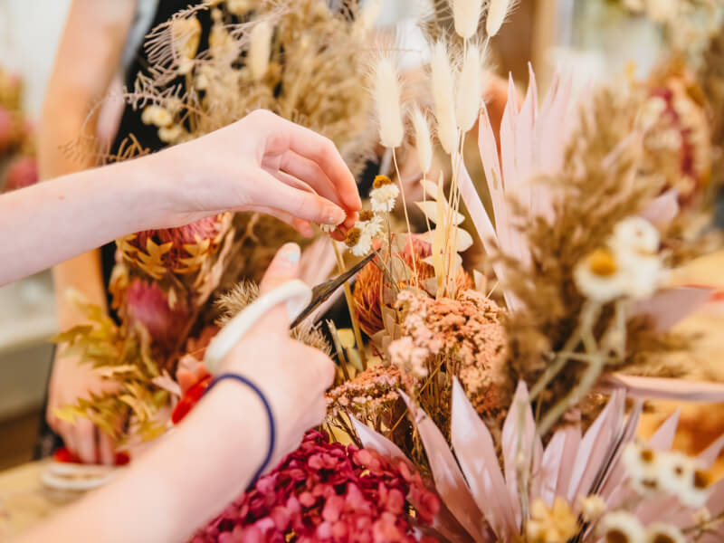 A person is making a hand tied bouquet from dried flowers at a floristry class in Manchester