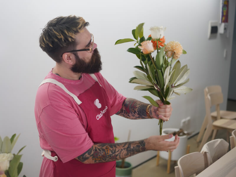 A man is holding a hand tied bouquet of peach and orange flowers