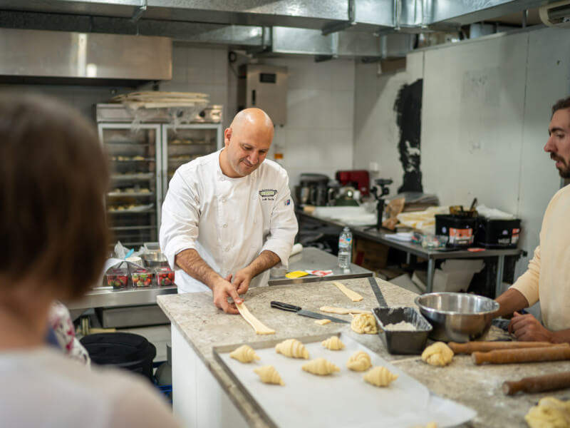 A teacher demonstrates pastry techniques at a baking class.
