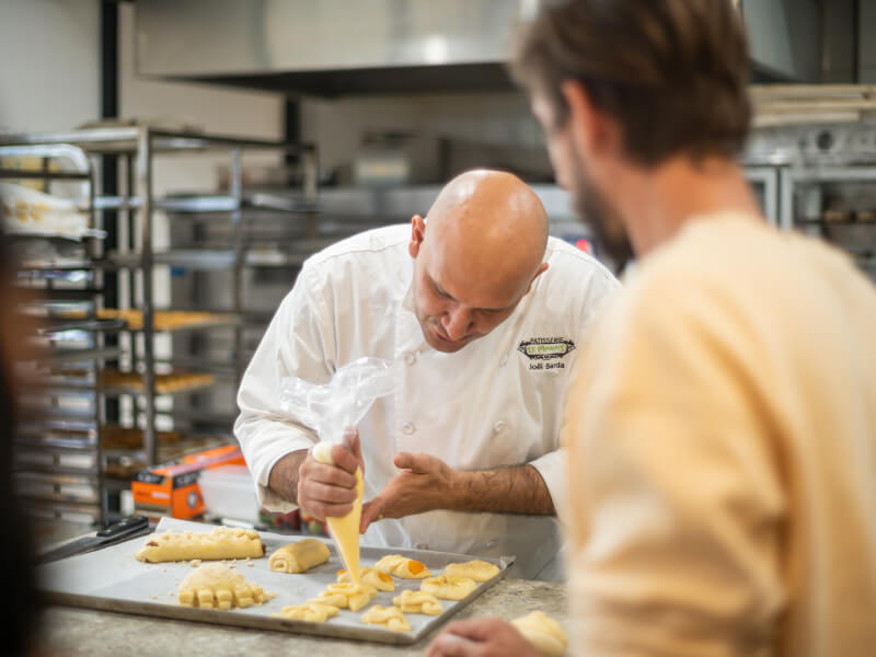A chef teaches a student how to make pastries at a patisserie class