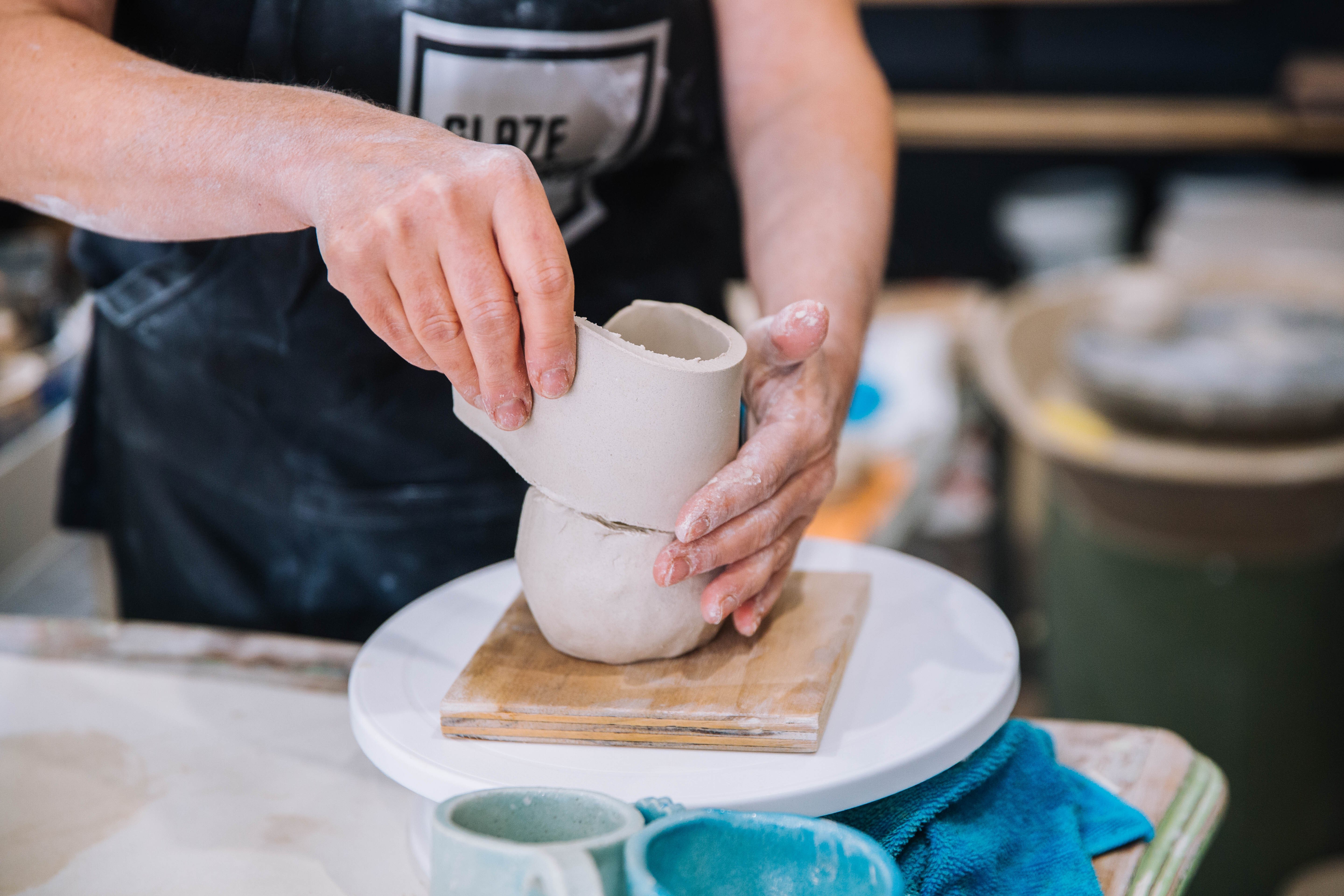 Hands using slab building to make clay into a small cup