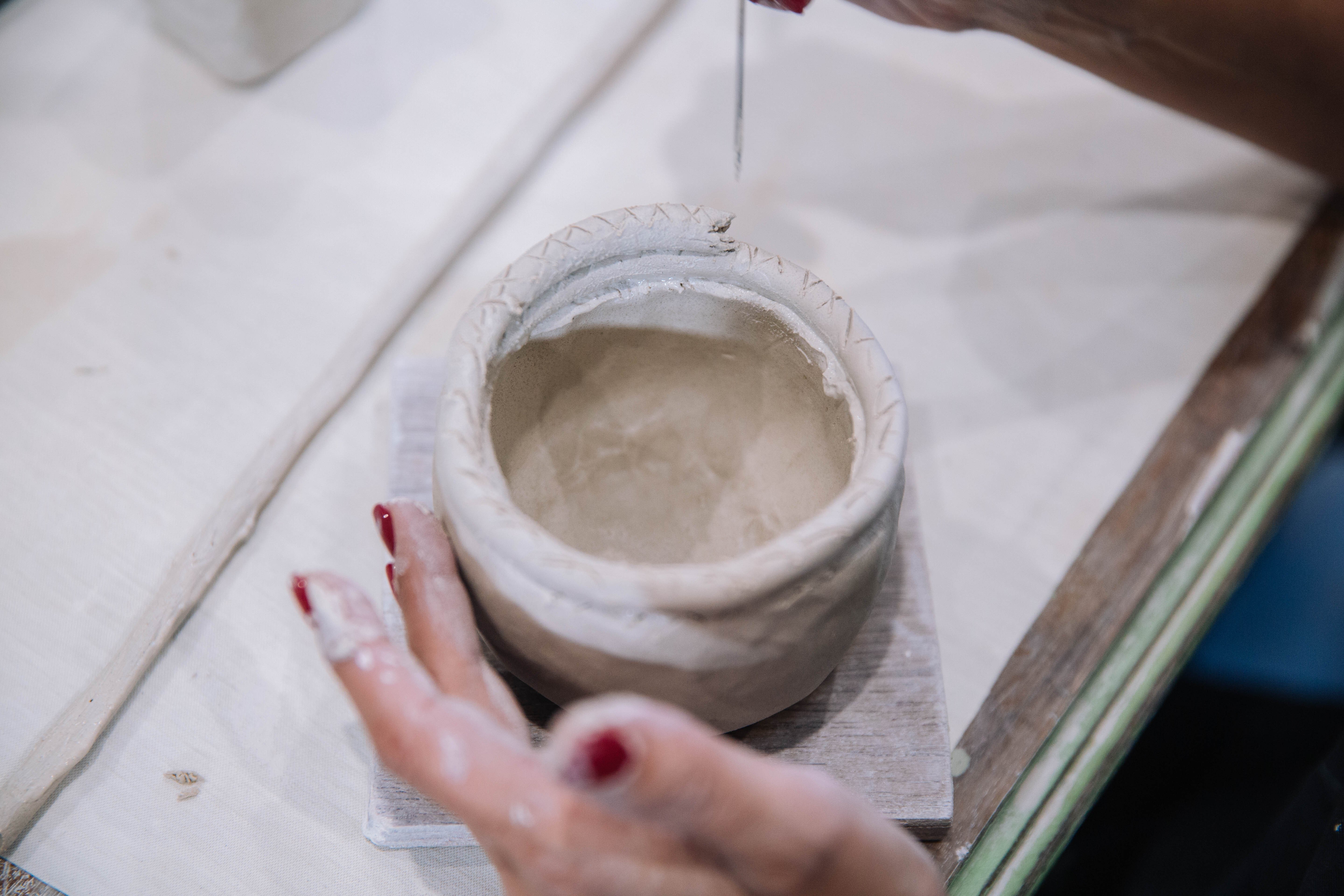 Close up of hands shaping coiled clay into a vessel