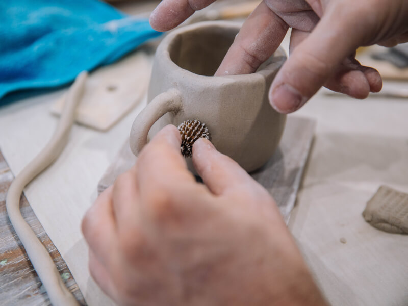 A closeup of a homemade clay cup being made.