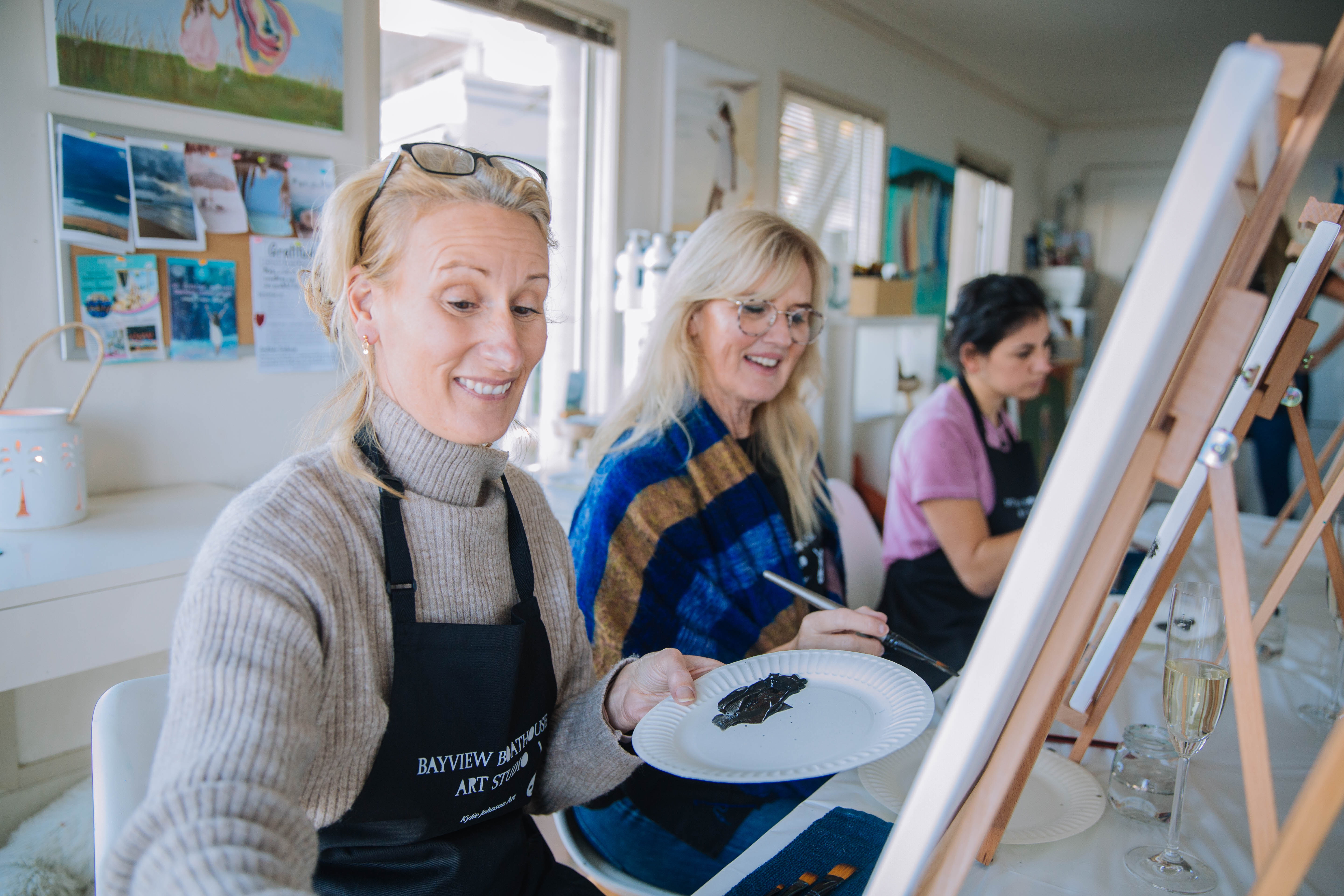 A group of women painting, sat at easels