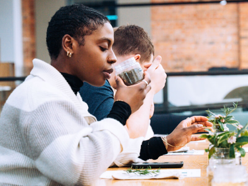 A person at a herbal workshop from Hackney Herbal smelling a jar of herbs