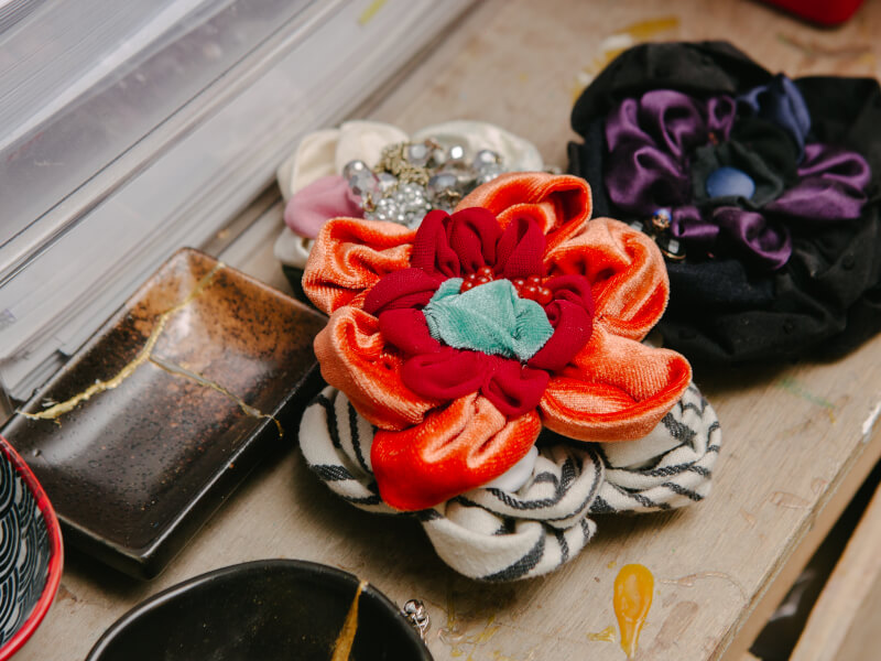 A selection of handmade fabric flowers sit on a wooden table