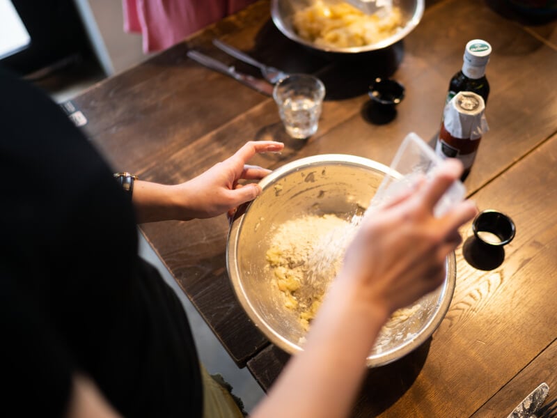 Hands pouring parmesan on handmade pasta