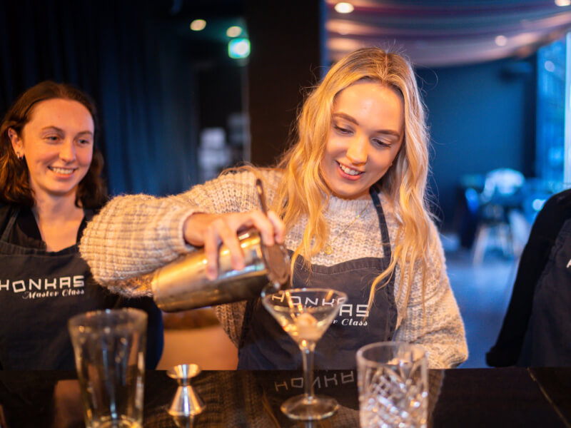 A woman pouring a cocktail in a mixology class.